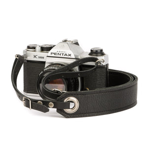 black leather camera strap on a Pentax camera with black leather end straps and brushed nickel grommets