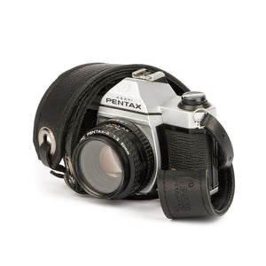 black leather camera strap wrapped around a Pentax camera with black leather end straps and brushed nickel grommets