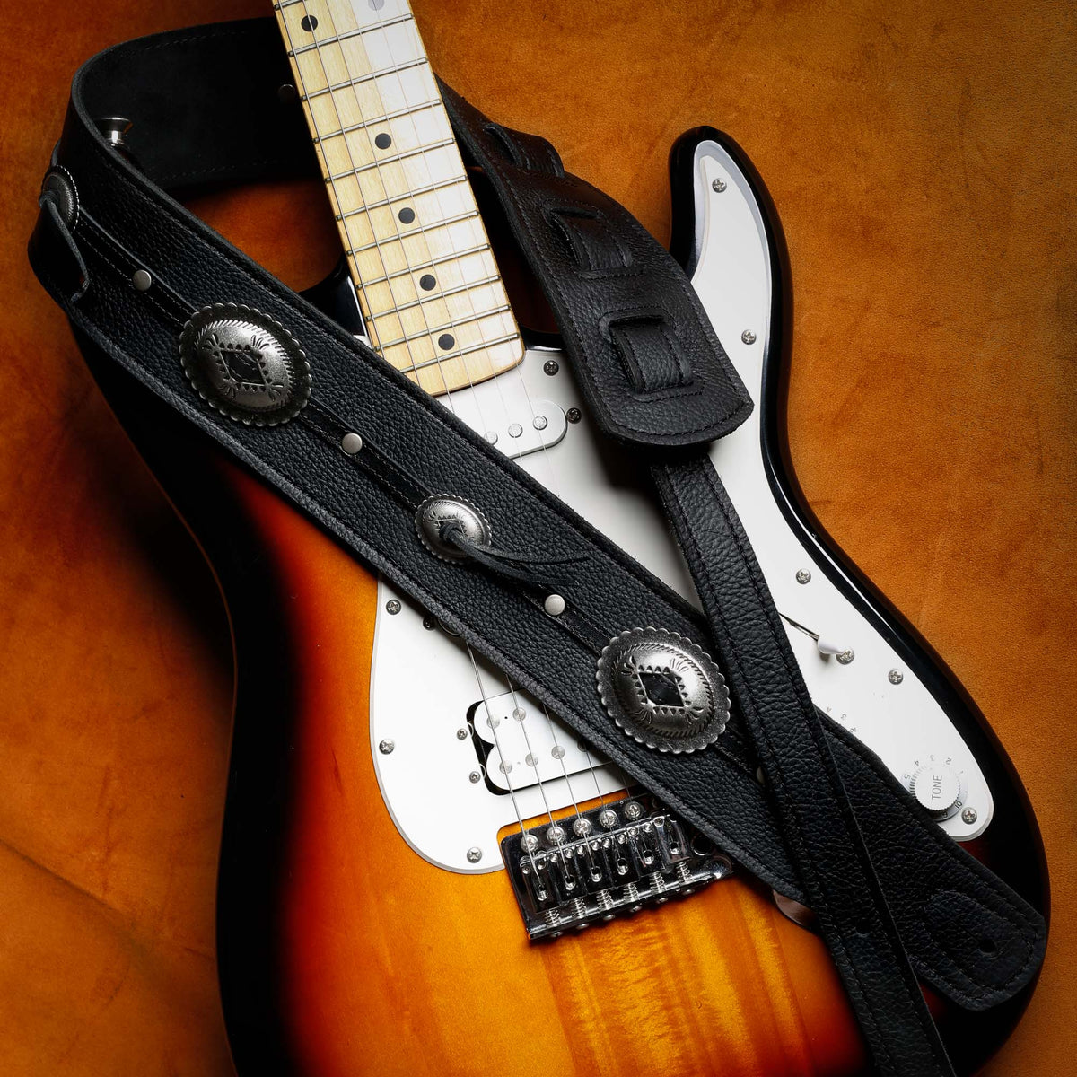 black leather guitar strap with silver Conchos guitar strap on a Fender Stratocaster