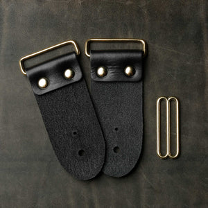 backside of black leather guitar strap end kit for a guitar strap with gold hardware