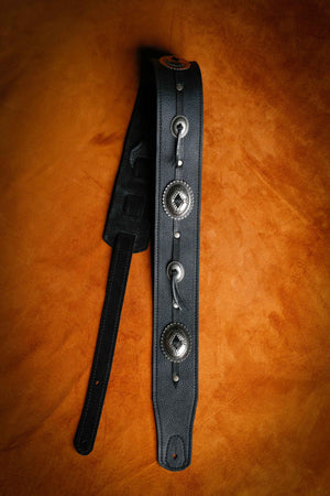 black leather with silver Concho guitar strap laying flat