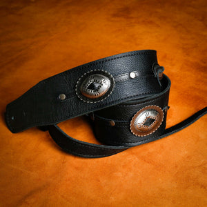 black leather with silver Concho guitar strap rolled up