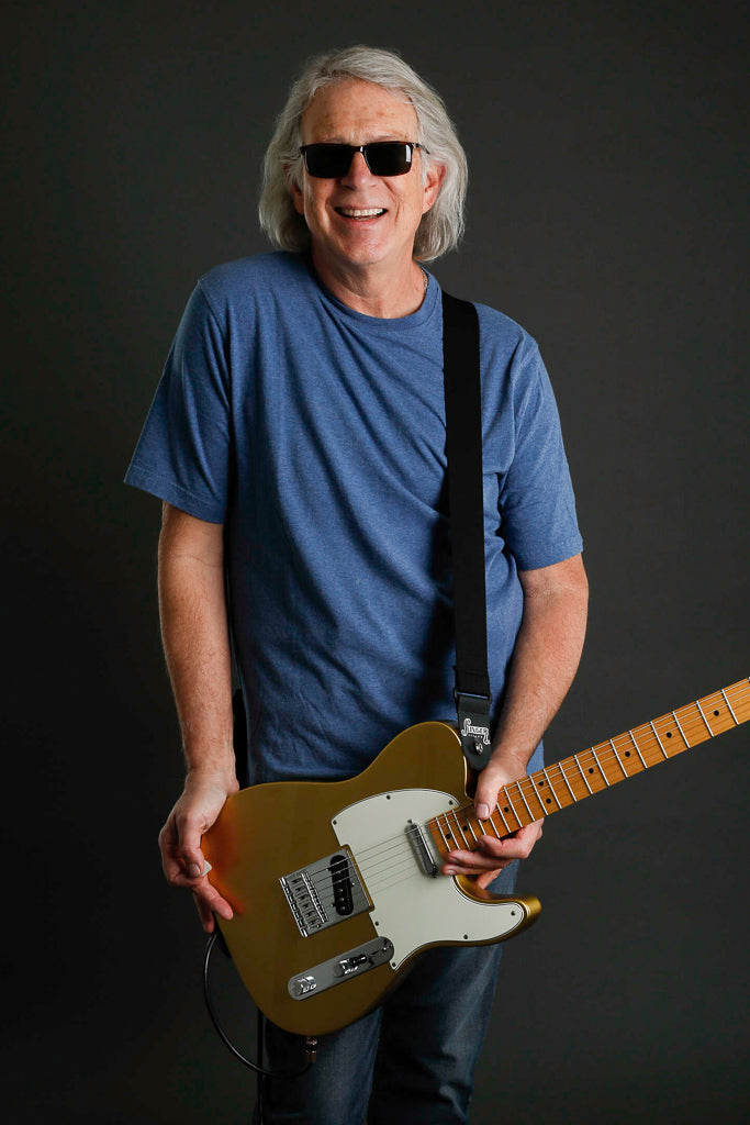 a stretched out comfort stretch elastic guitar strap from Slinger Straps holding  a Fender Telecaster guitar